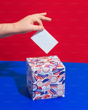 a person's hand throwing a piece of paper into a gift box