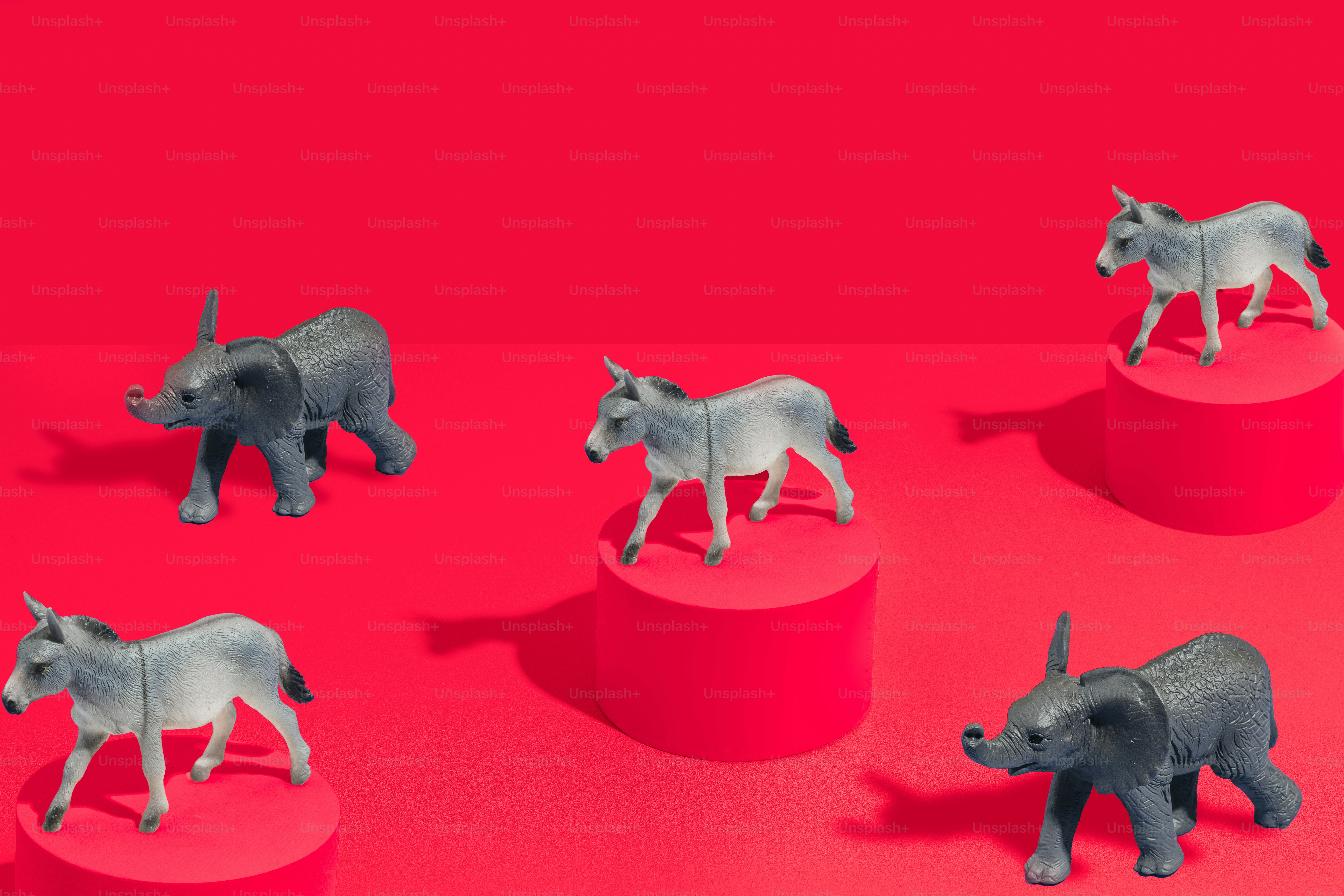 Un grupo de figurillas de rinocerontes sentadas sobre una superficie roja