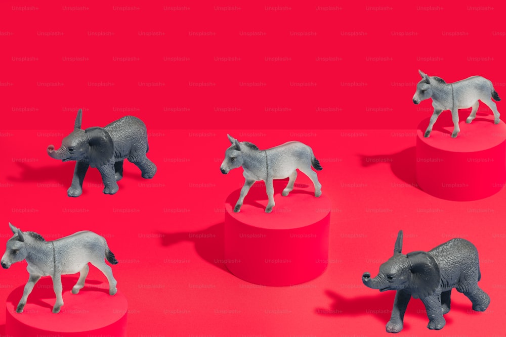a group of rhino figurines sitting on top of a red surface