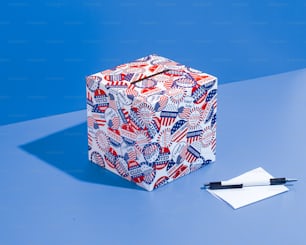 a paper cube with a pen on top of it