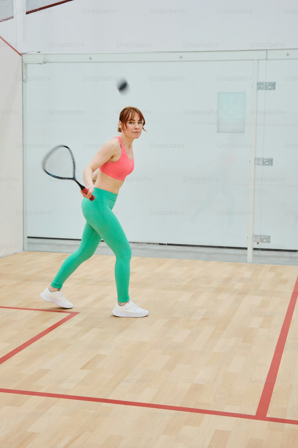 a woman is playing tennis on a hard wood floor