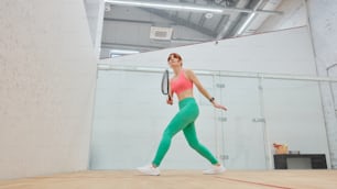 a woman in a pink top and green leggings holding a tennis racket