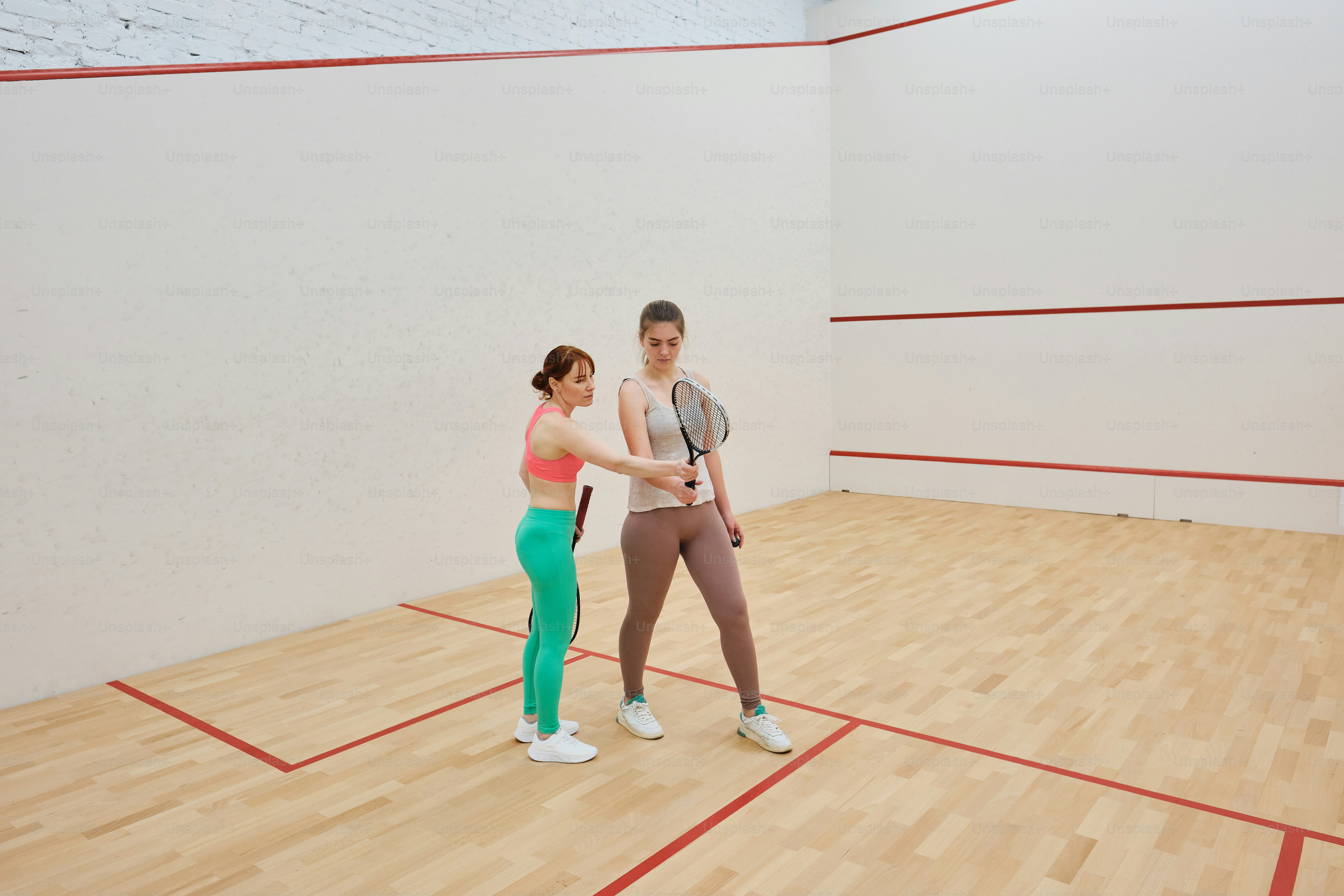 Una mujer con un top rosa y polainas verdes sosteniendo un rac de tenis ...