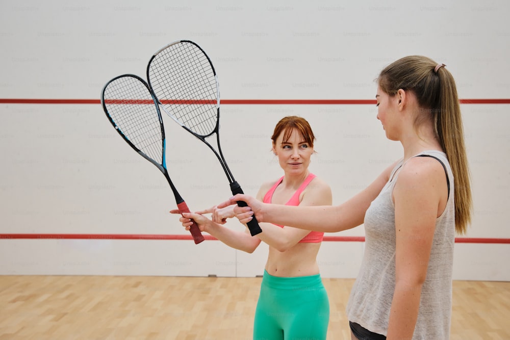 a woman holding a tennis racquet next to another woman