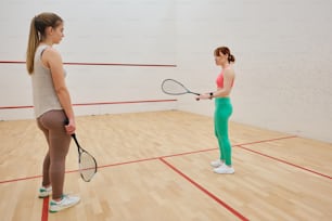 a woman holding a tennis racquet on top of a hard wood floor