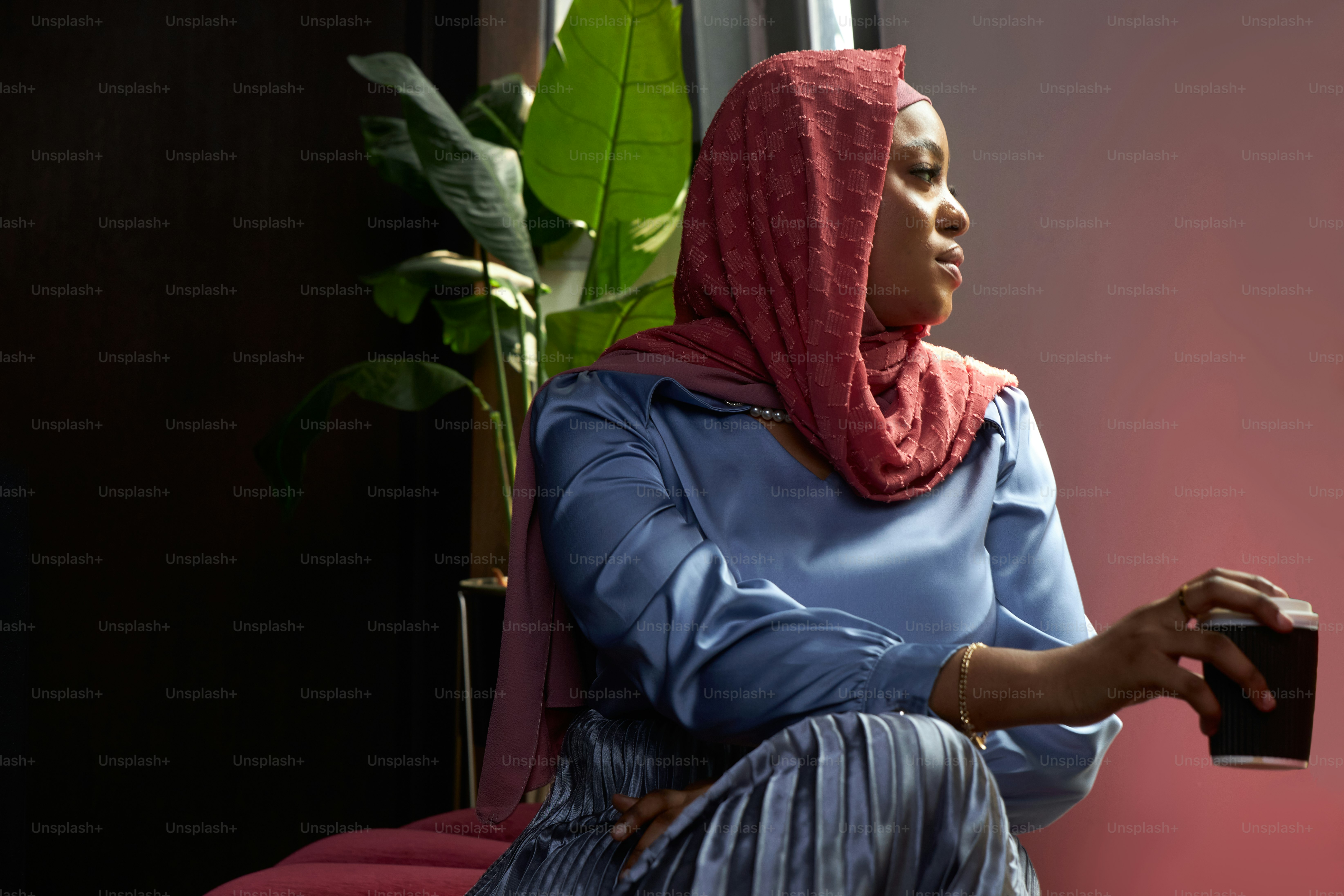 eine Frau, die auf einem Stuhl sitzt und eine Tasse hält