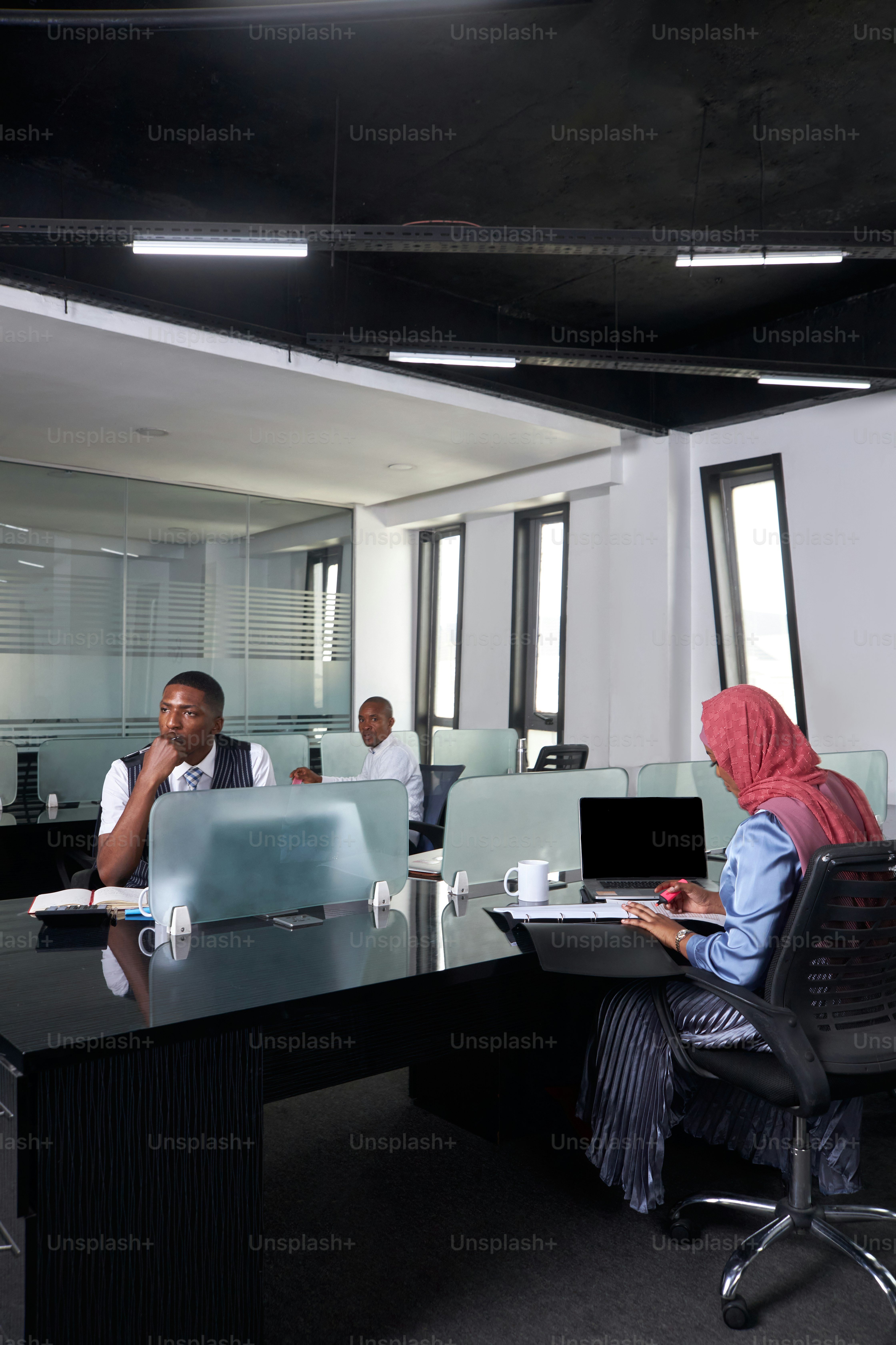 a group of people sitting around a table with laptops
