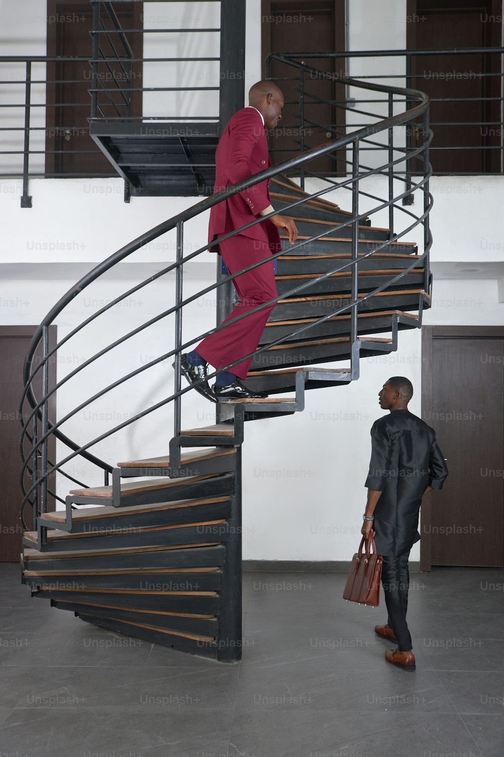 a man in a red suit is standing on a stair case