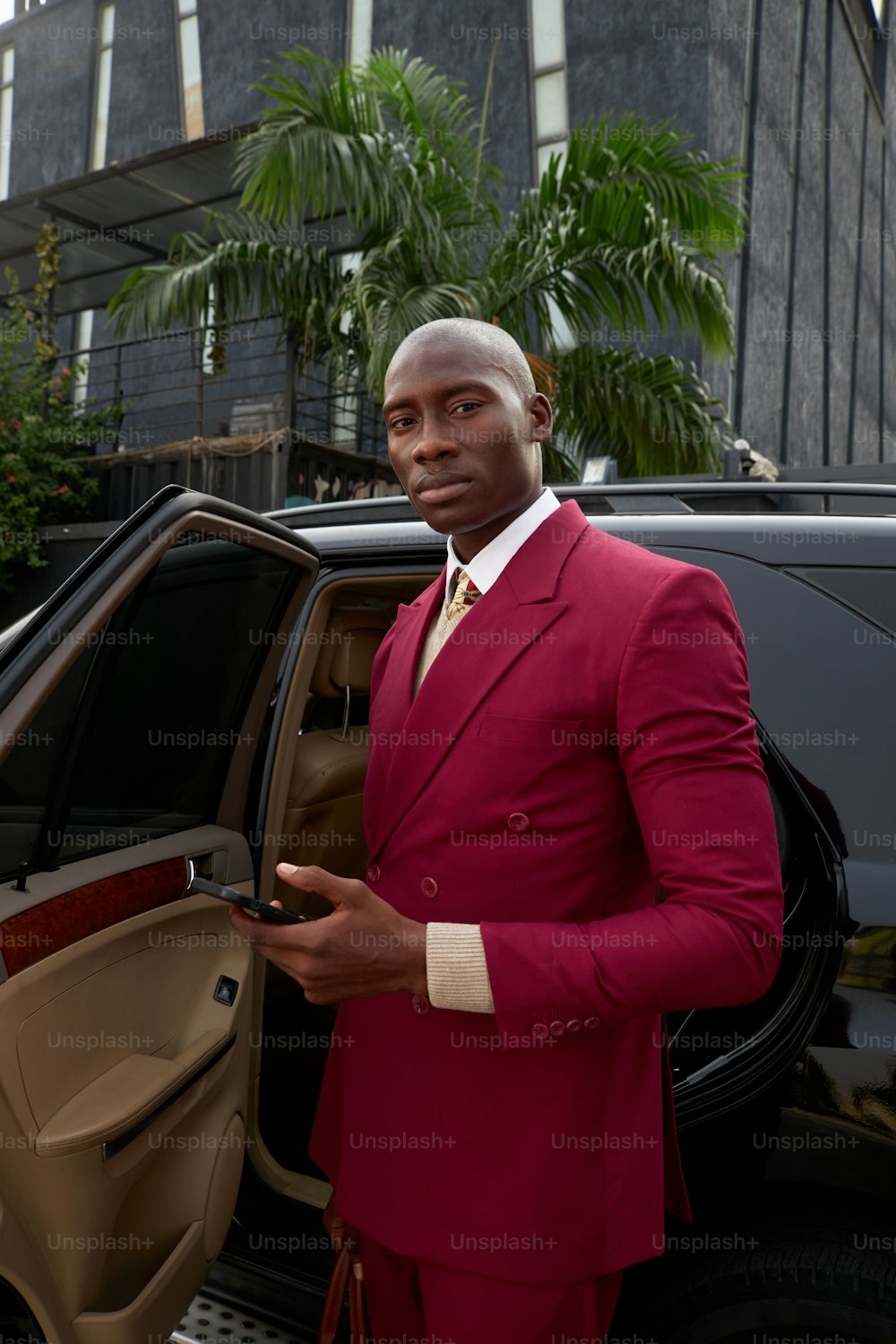 a man in a red suit standing next to a car