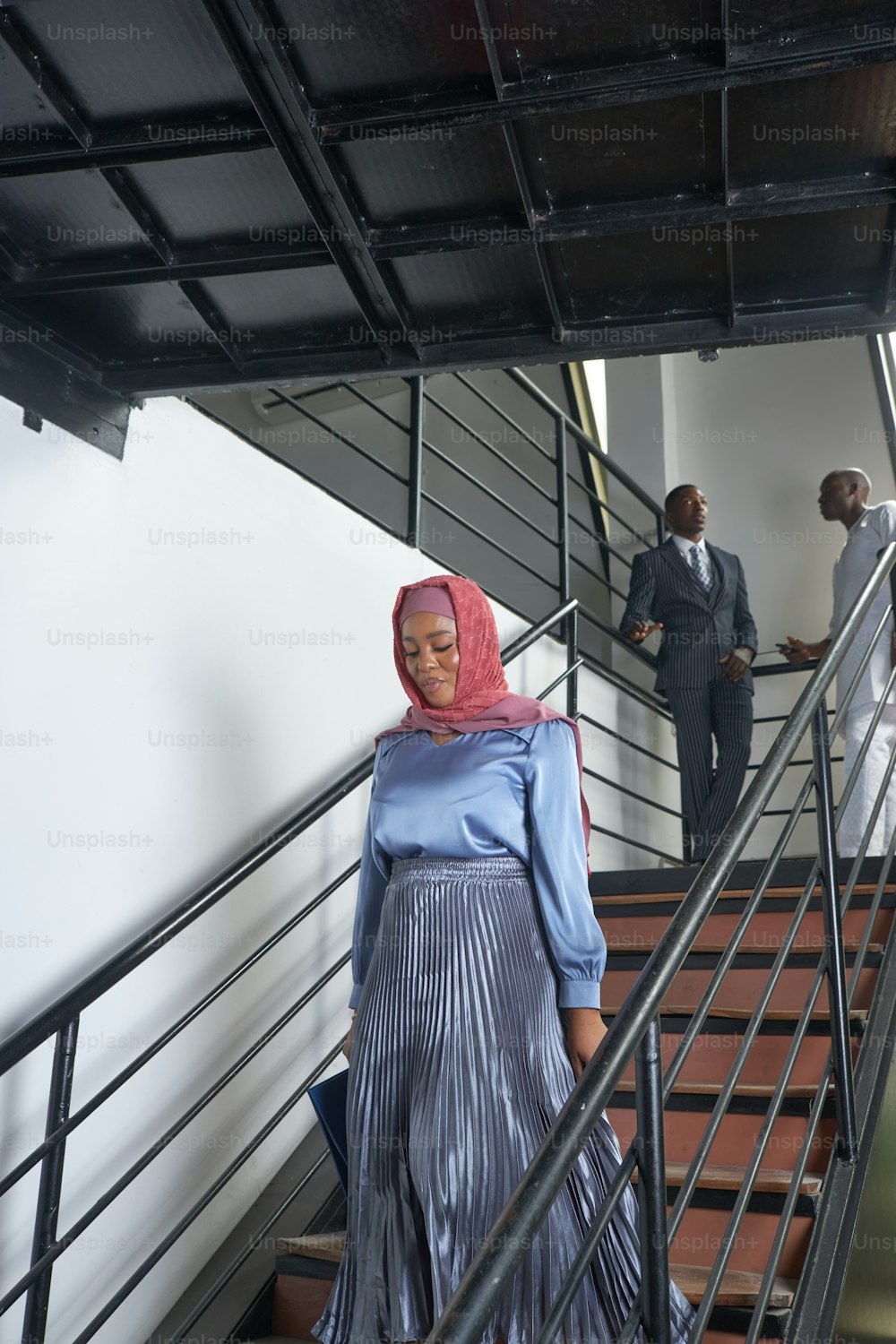 a woman in a blue dress walking down a set of stairs