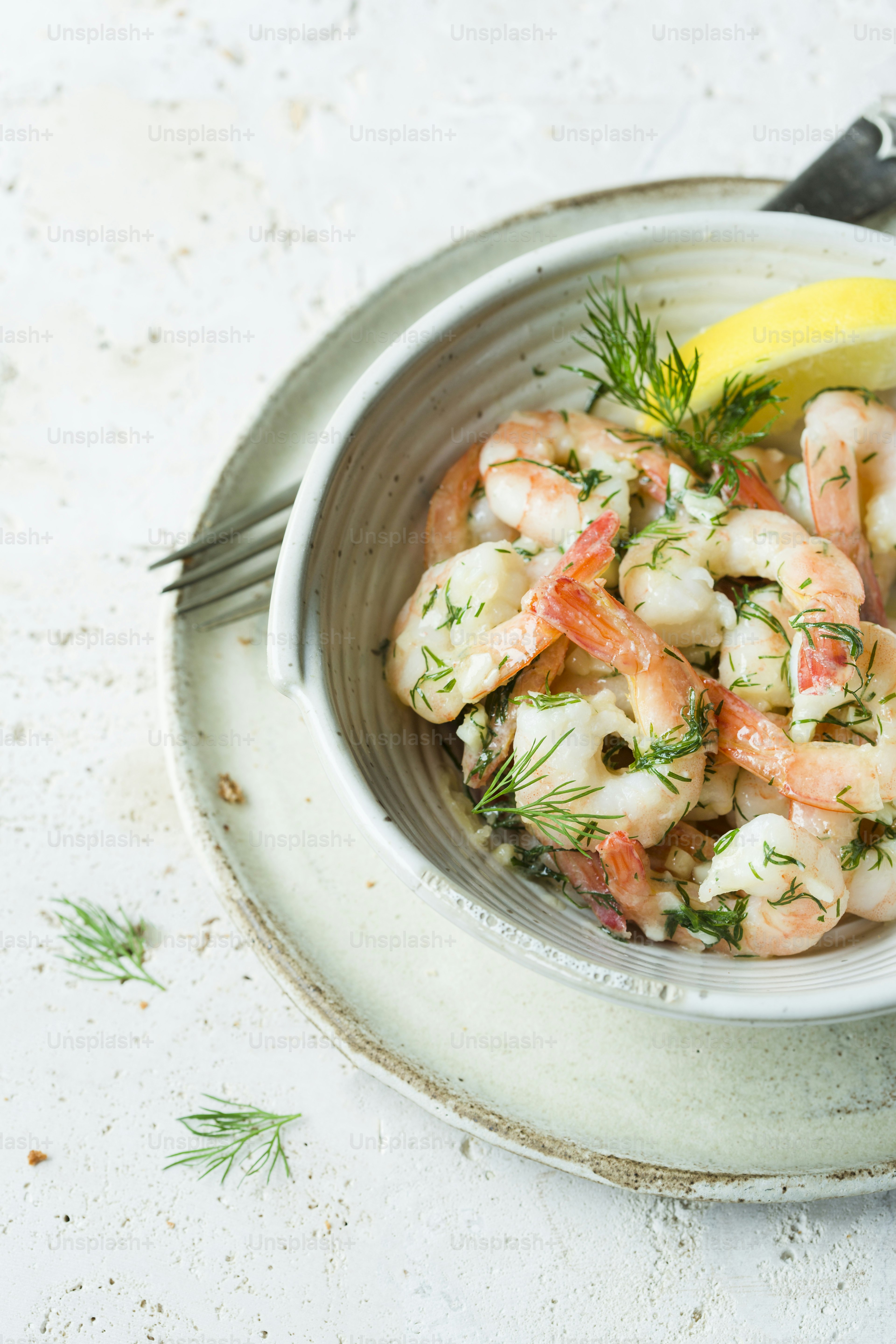a bowl of shrimp with a lemon wedge on the side