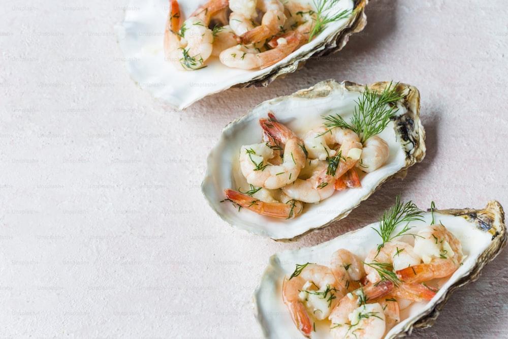three open oysters with shrimp and garnish on them