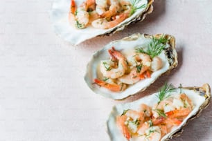 three open oysters with shrimp and garnish on them