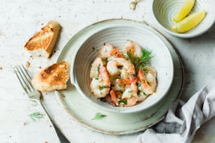 a bowl of shrimp and bread on a table