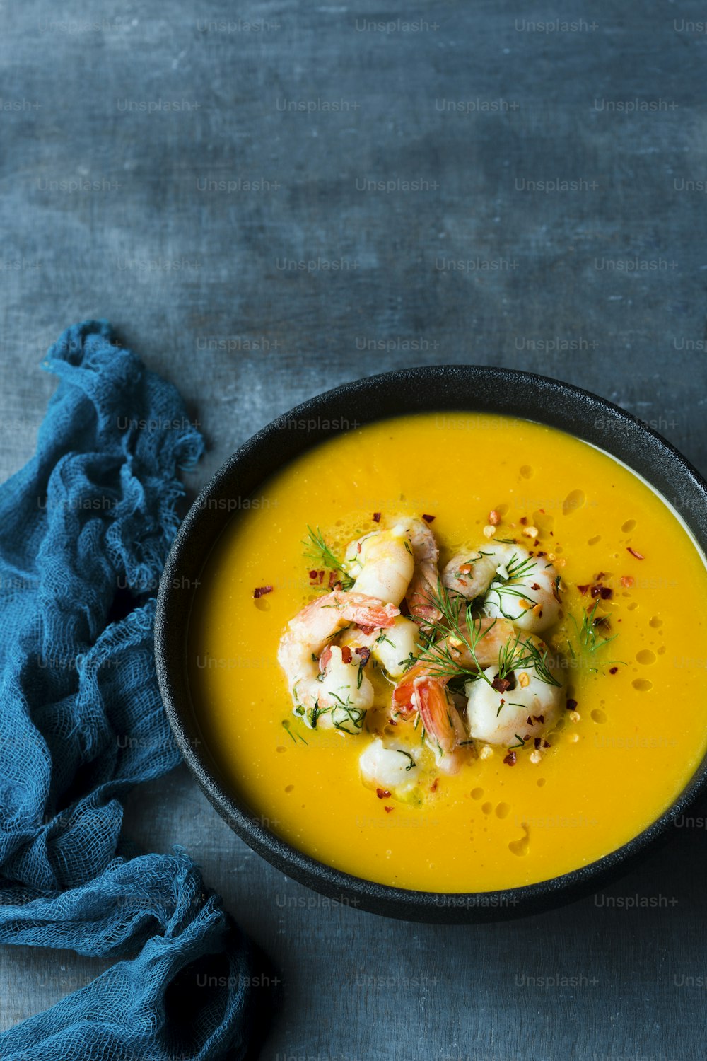 a bowl of soup with shrimp and garnishes