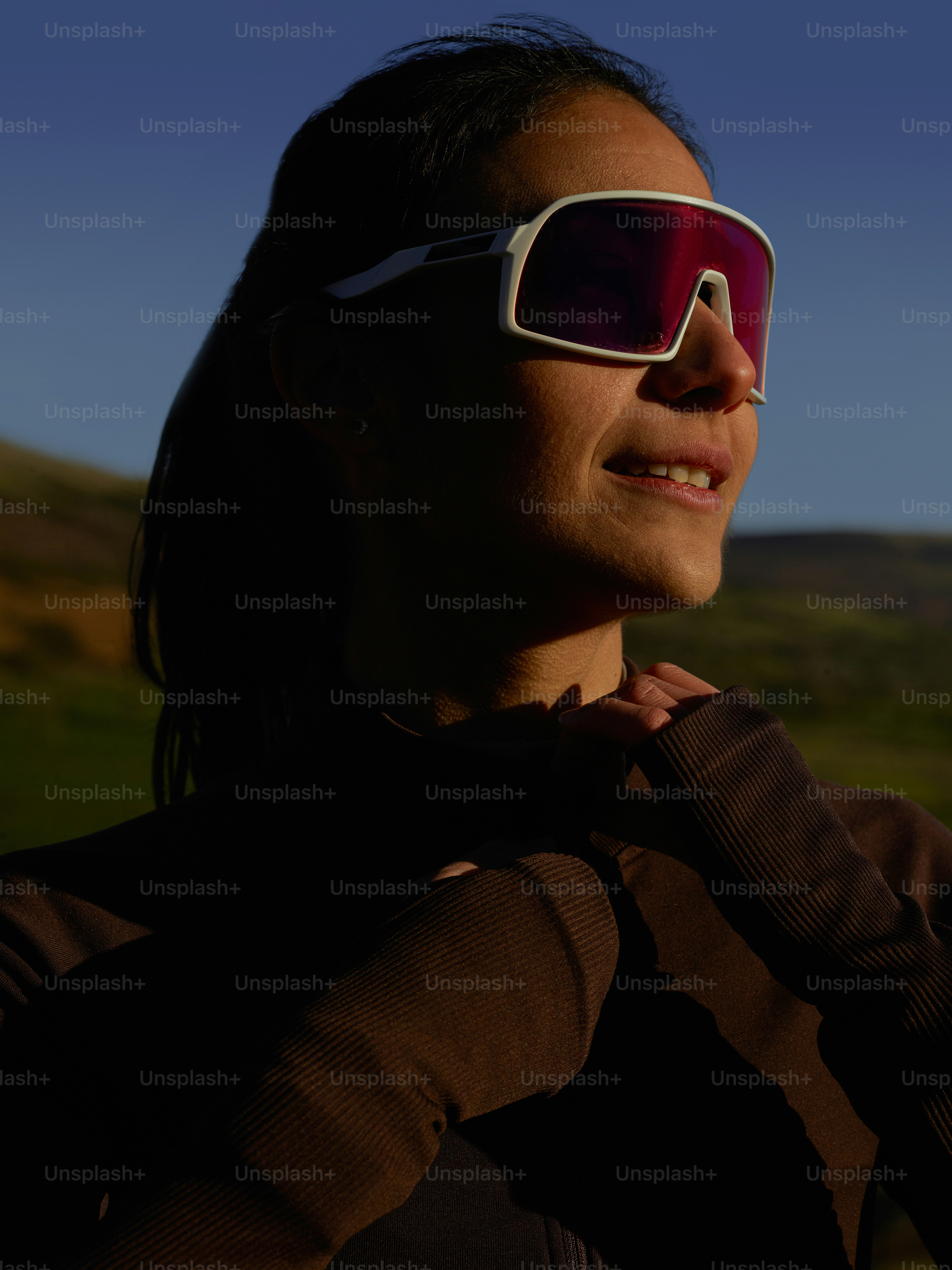 Eine Frau mit Sonnenbrille und brauner Jacke