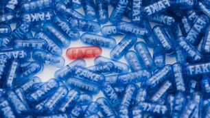 une pilule rouge posée sur une pile de pilules bleues