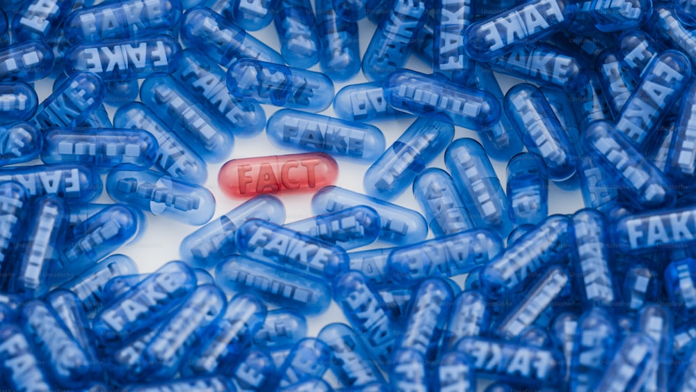 una pillola rossa seduta sopra una pila di pillole blu