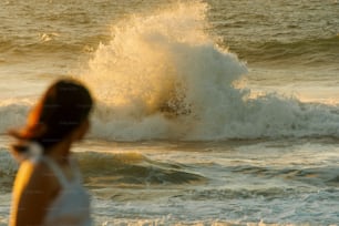 a woman standing in front of a wave in the ocean