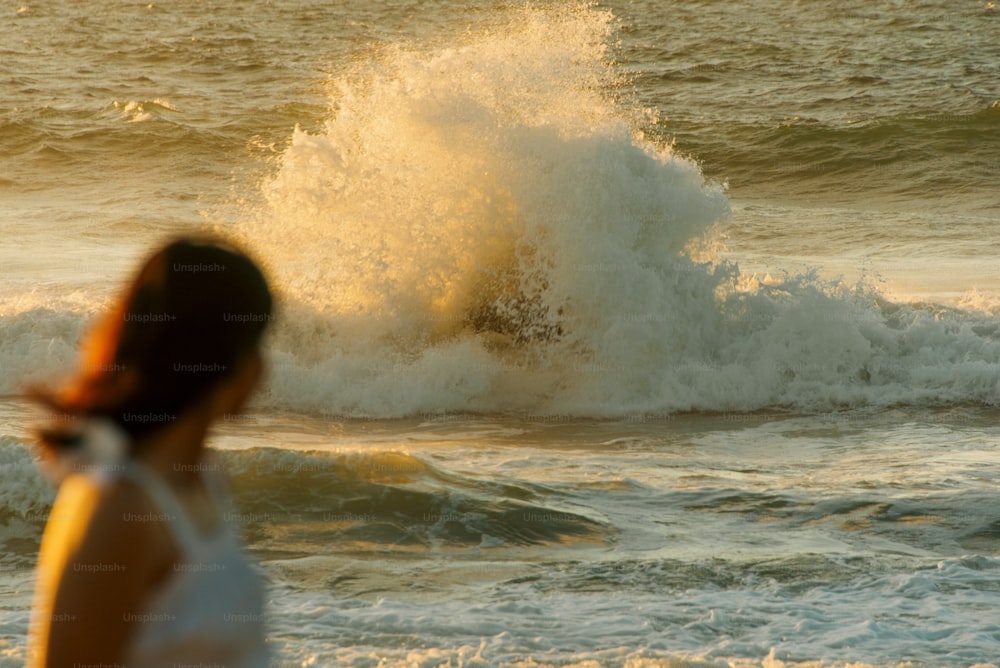 a woman standing in front of a wave in the ocean