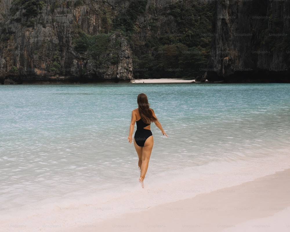 a woman in a bikini running on the beach