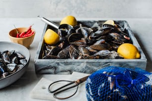 a bowl of mussels next to a bowl of lemons