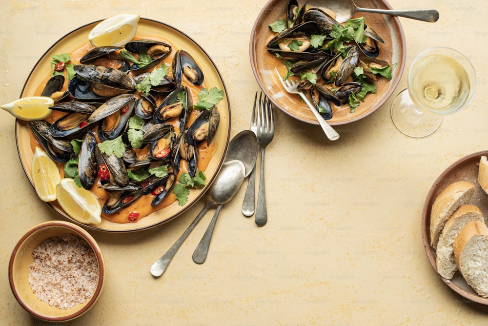 a plate of mussels, bread, and salad on a table