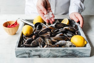 a tray of mussels and lemons on a table