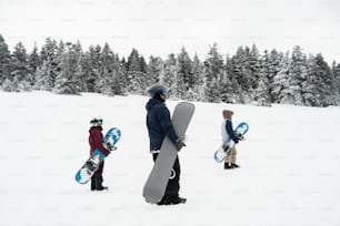 un groupe de personnes transportant des planches à neige à travers un champ enneigé