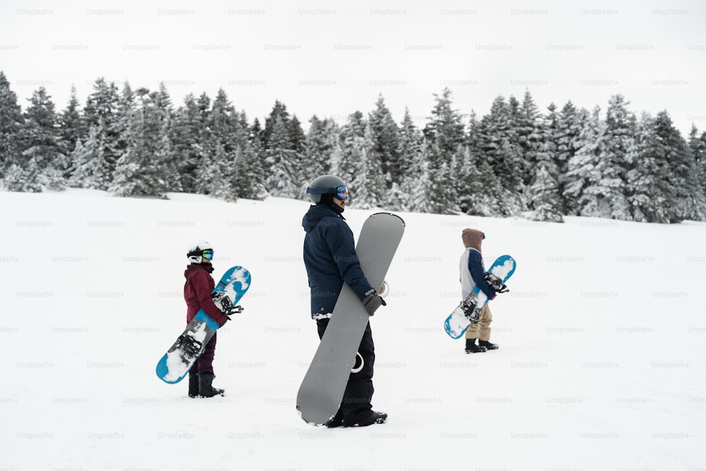 a group of people carrying snowboards across a snow covered field