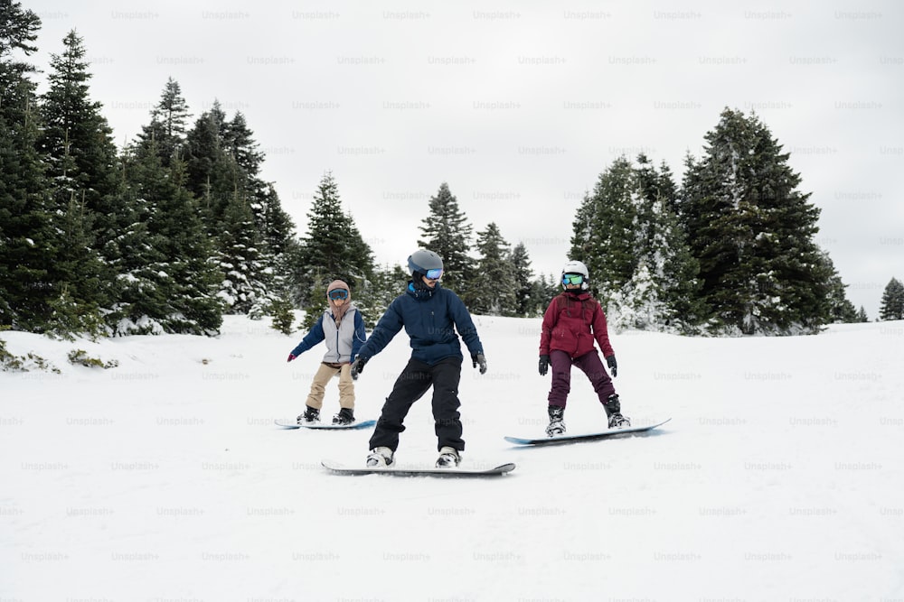 雪に覆われた斜面をスノーボードで駆け下りる人々のグループ