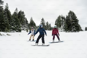 a group of people riding snowboards down a snow covered slope