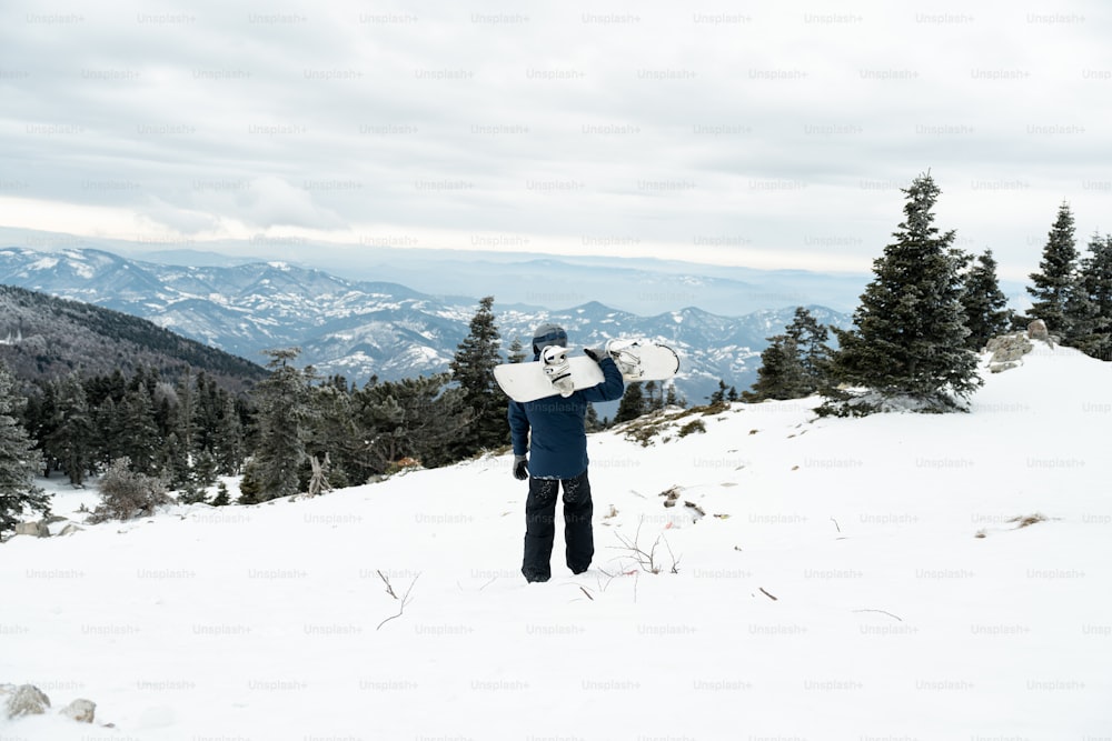 a man holding a snowboard on top of a snow covered slope