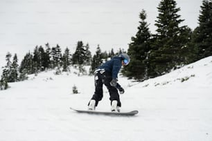 a man riding a snowboard down a snow covered slope