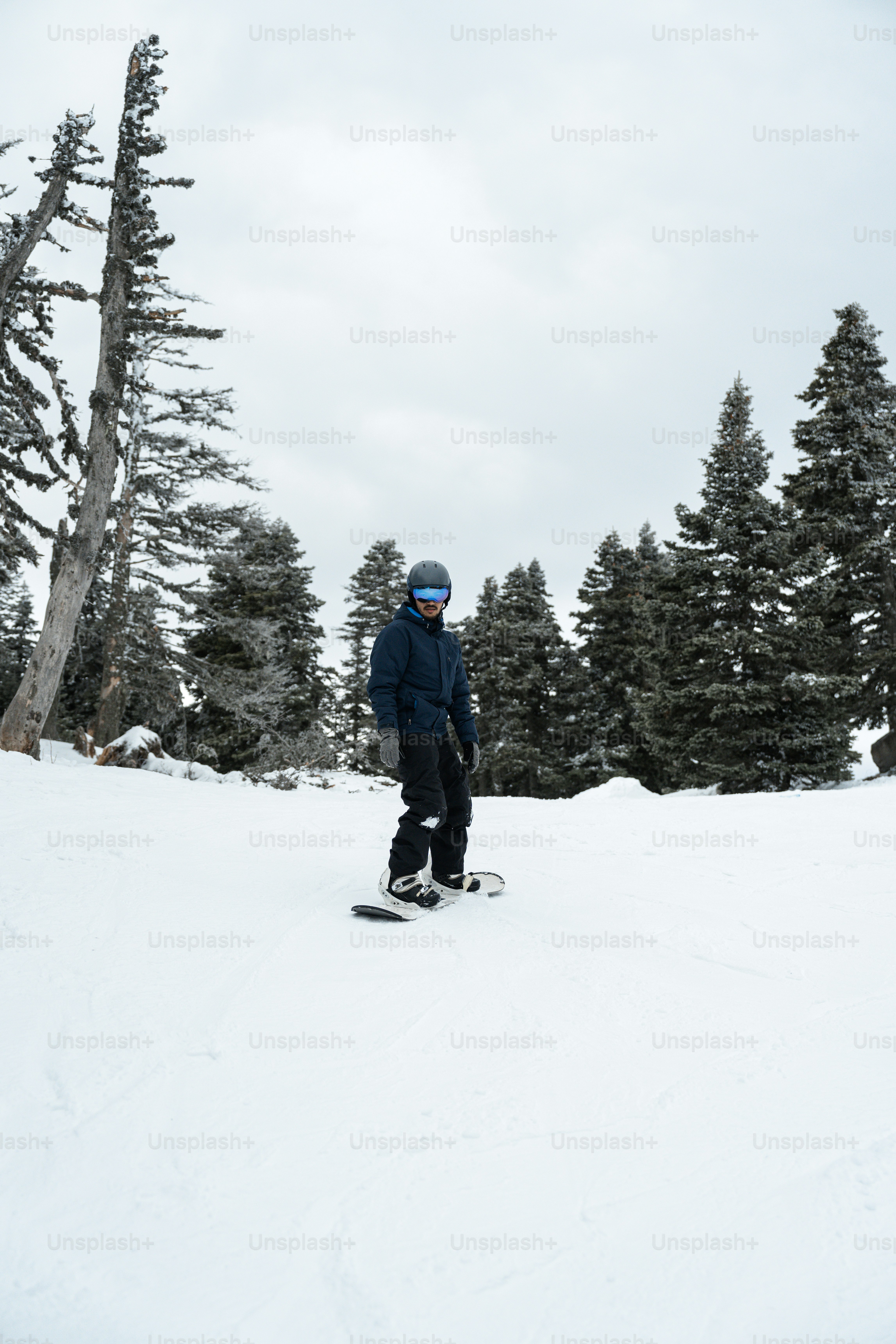 a man riding a snowboard down a snow covered slope
