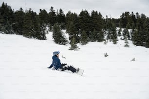 a person sitting in the snow with a snowboard