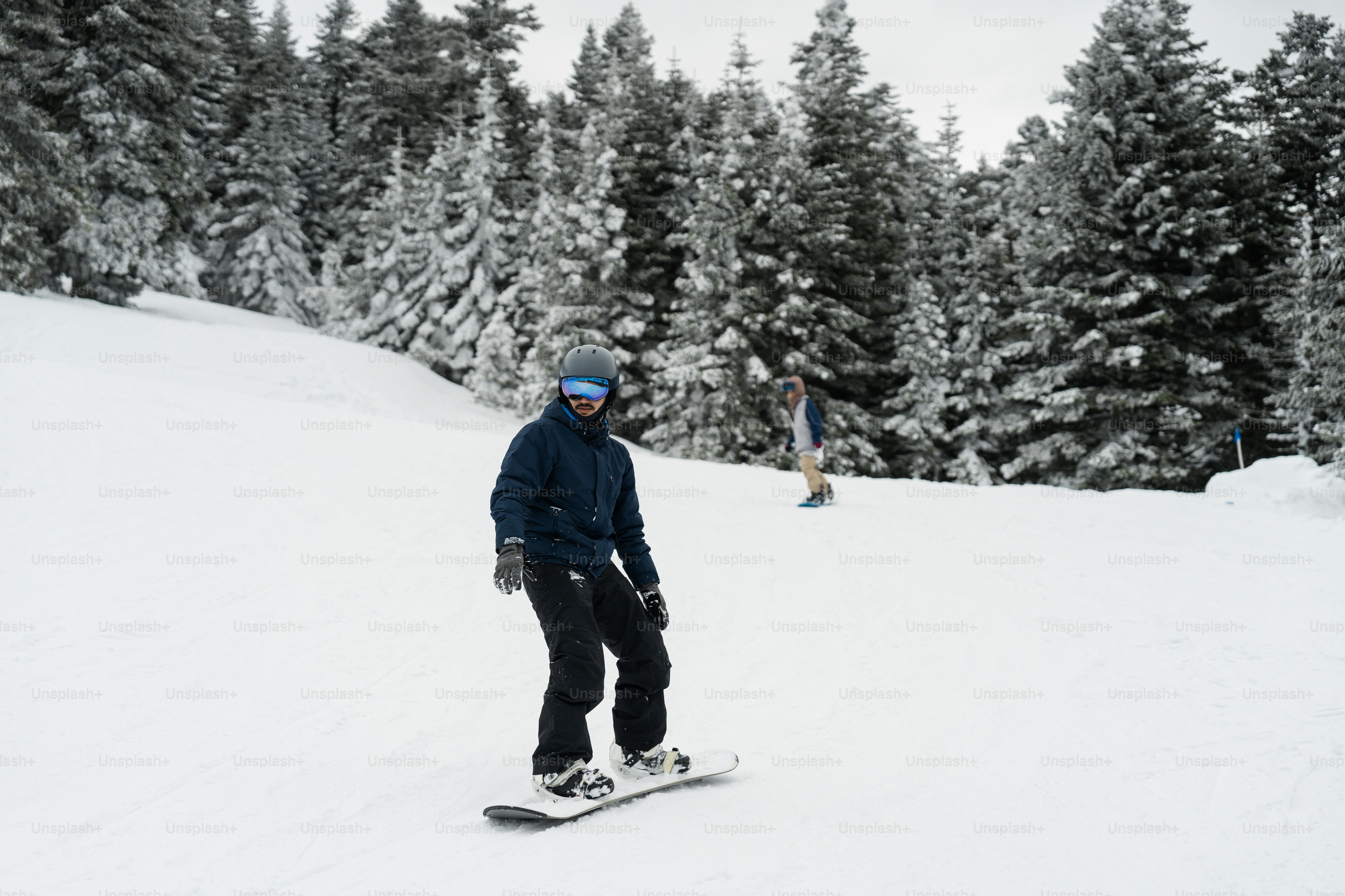 A man riding a snowboard down a snow covered slope photo – Forest Image ...