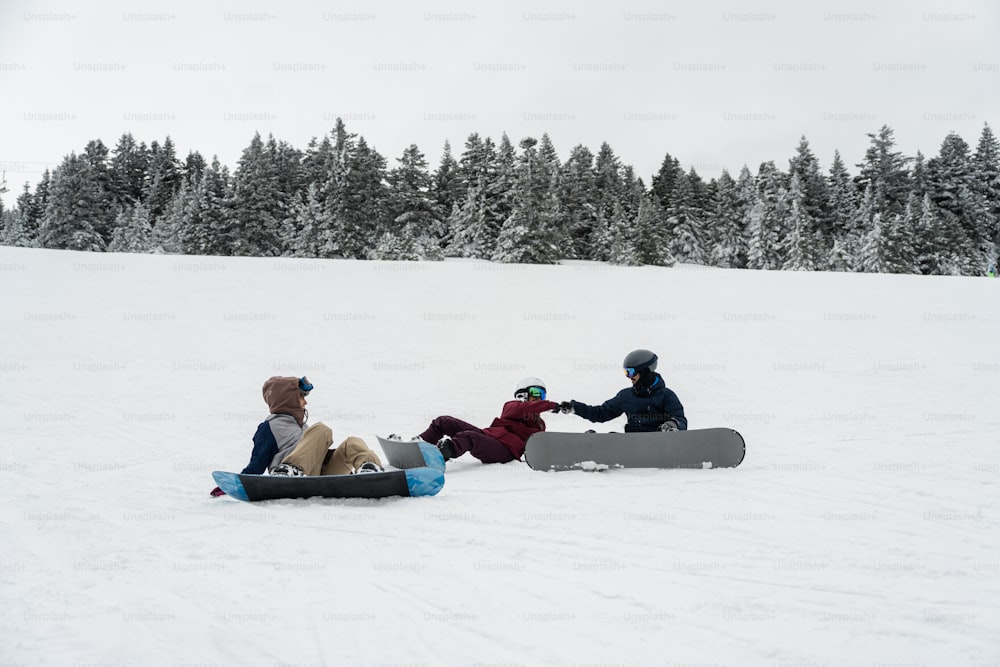 a group of people sitting on top of a snow covered slope