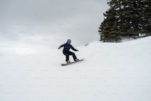 雪に覆われた斜面をスノーボードで駆け下りる男性