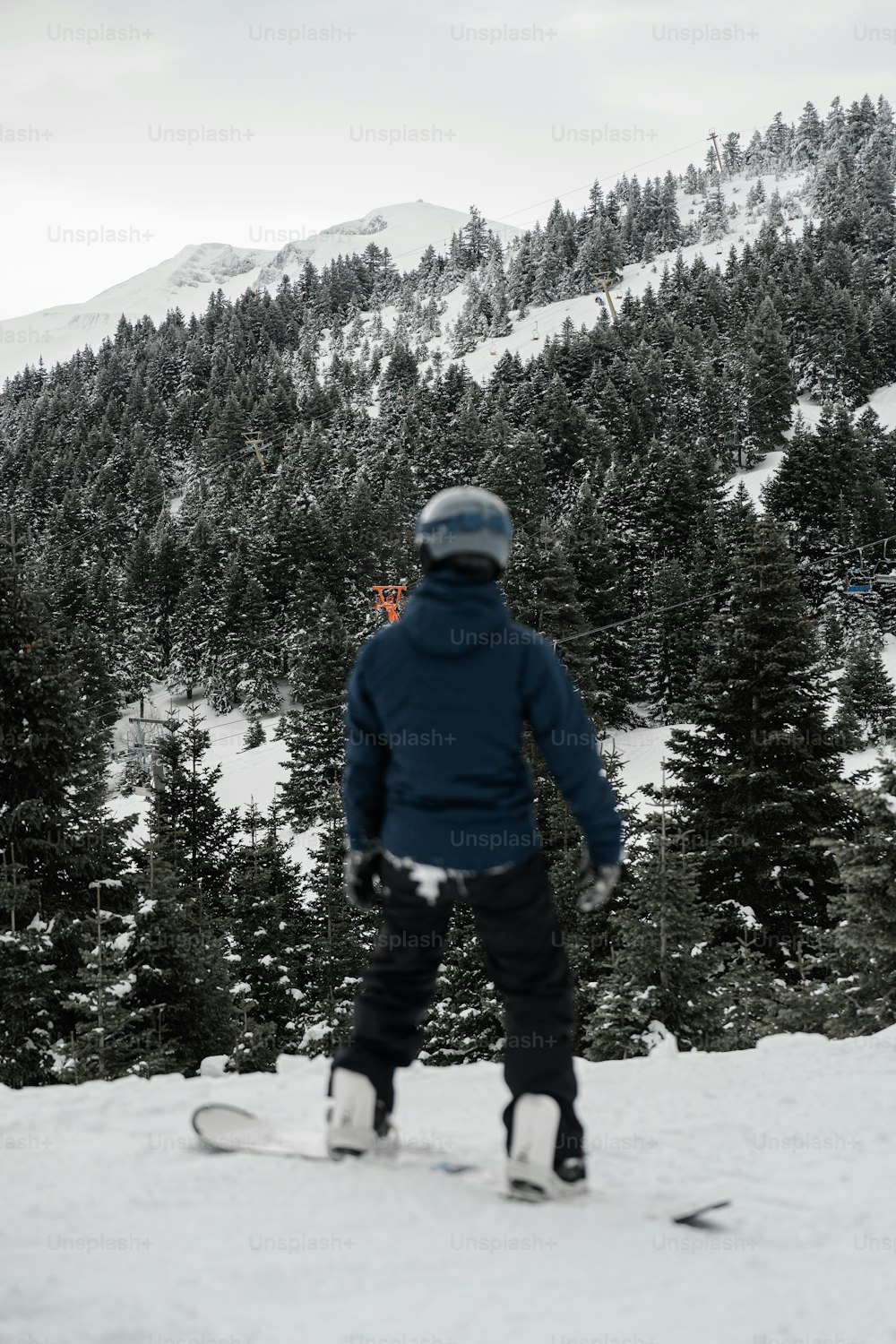 雪に覆われた斜面をスノーボードで駆け下りる人