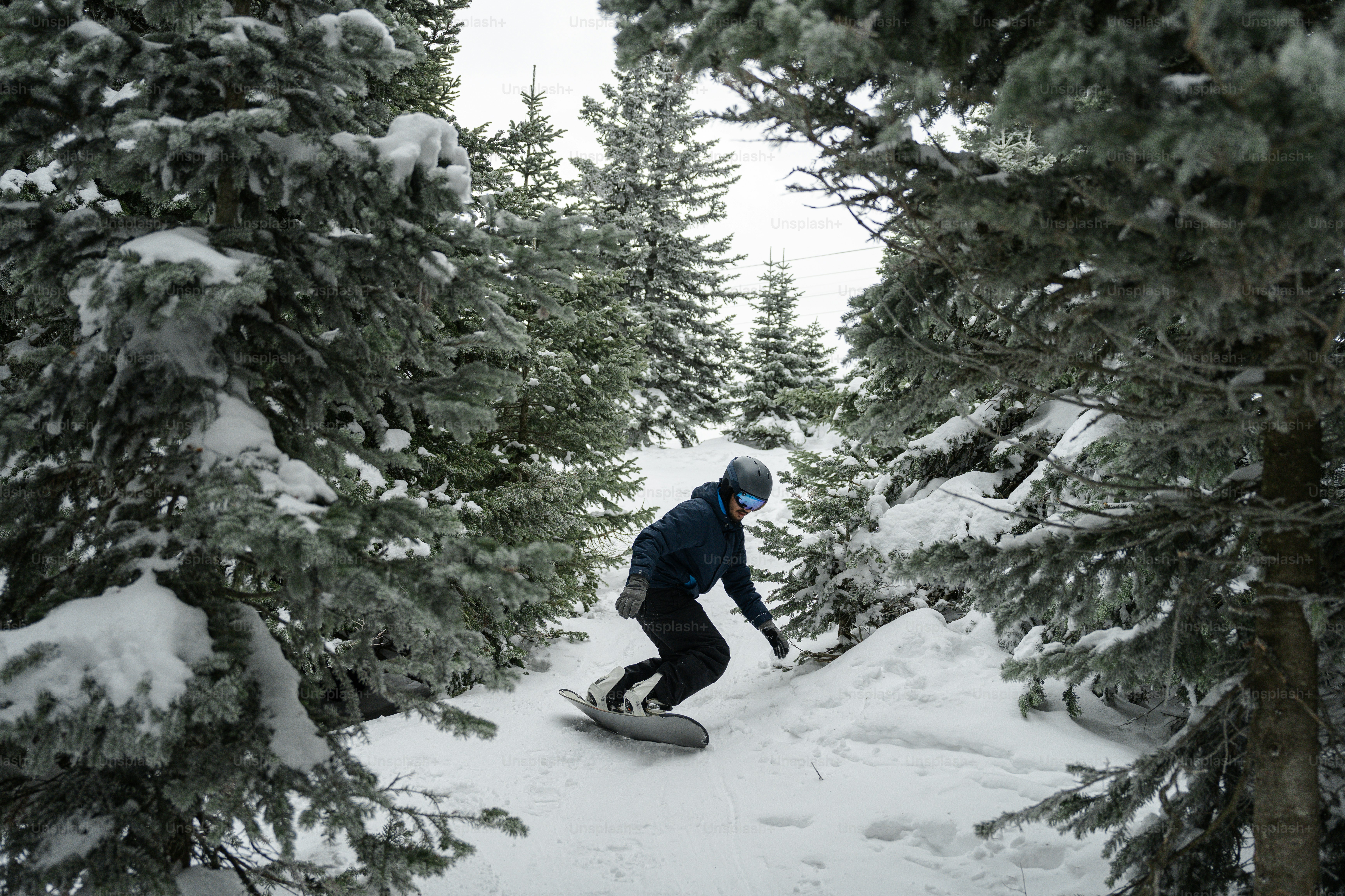 A man riding a snowboard down a snow covered slope photo – Snow Image ...