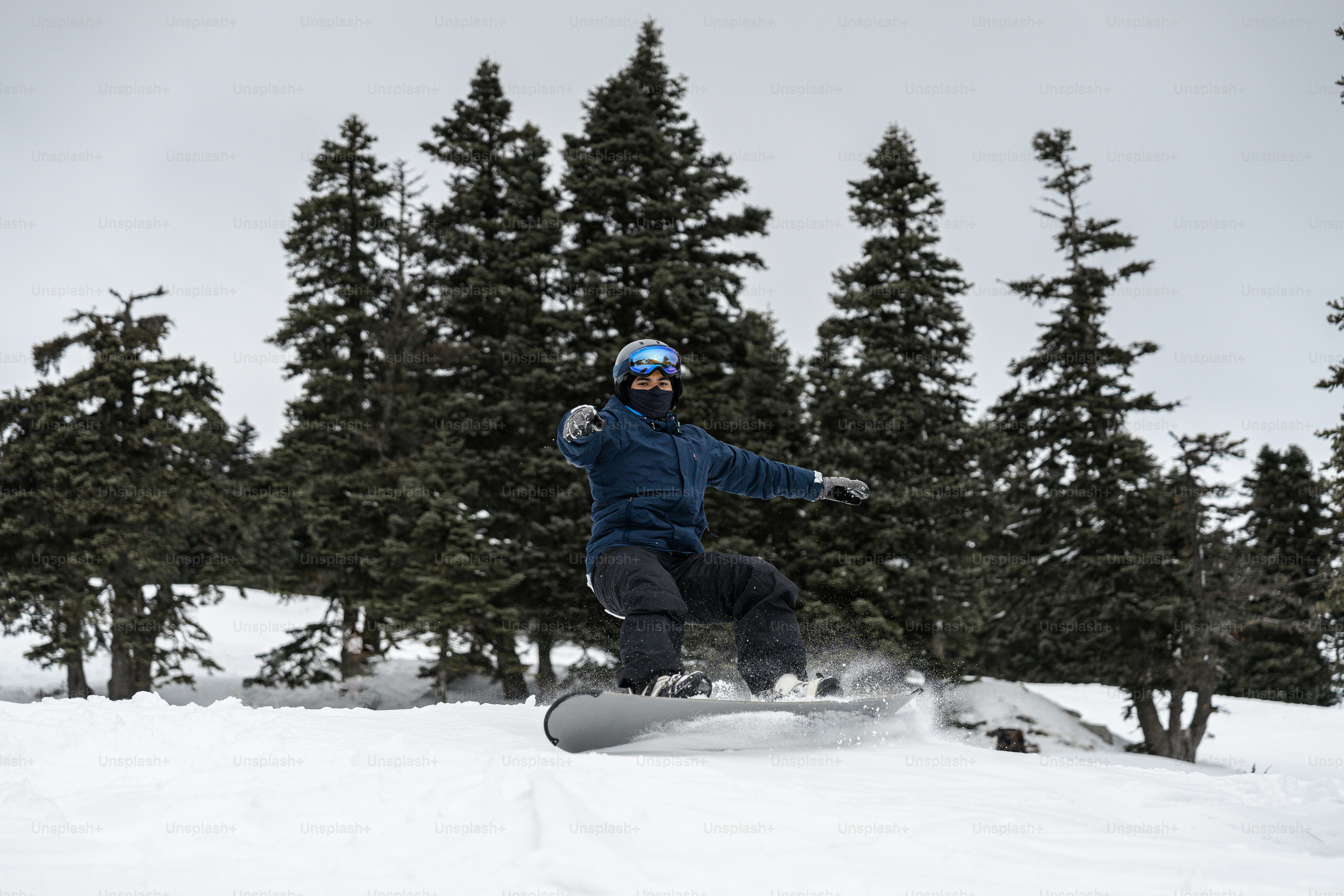 A man riding a snowboard down a snow covered slope photo – Snowboarding ...