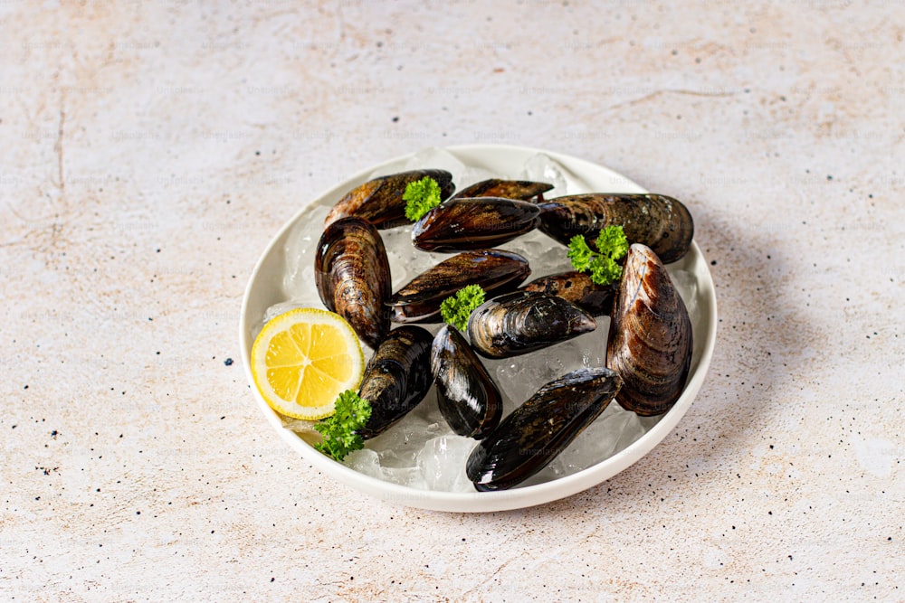 a white plate topped with mussels and a lemon wedge