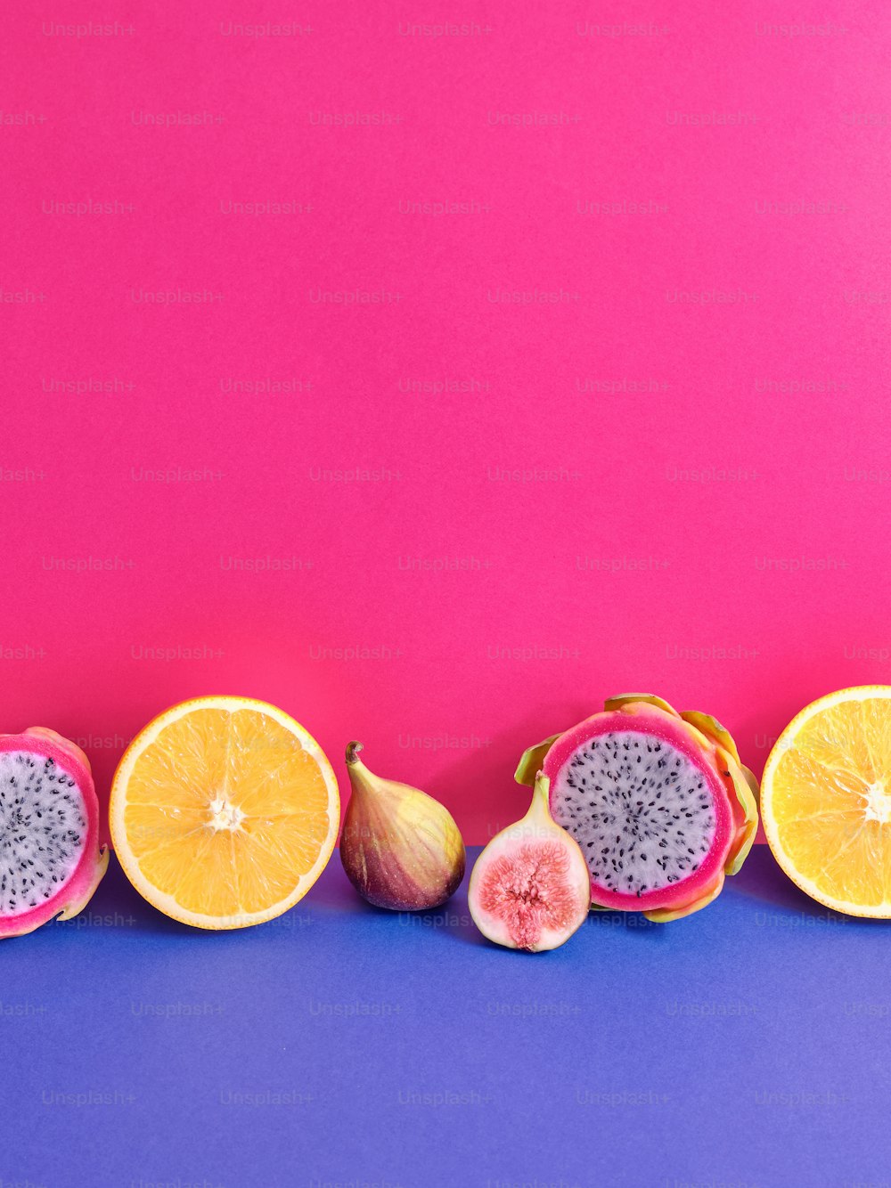 a group of fruit cut in half on a purple and pink background
