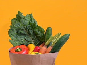 a brown paper bag filled with vegetables on a yellow background