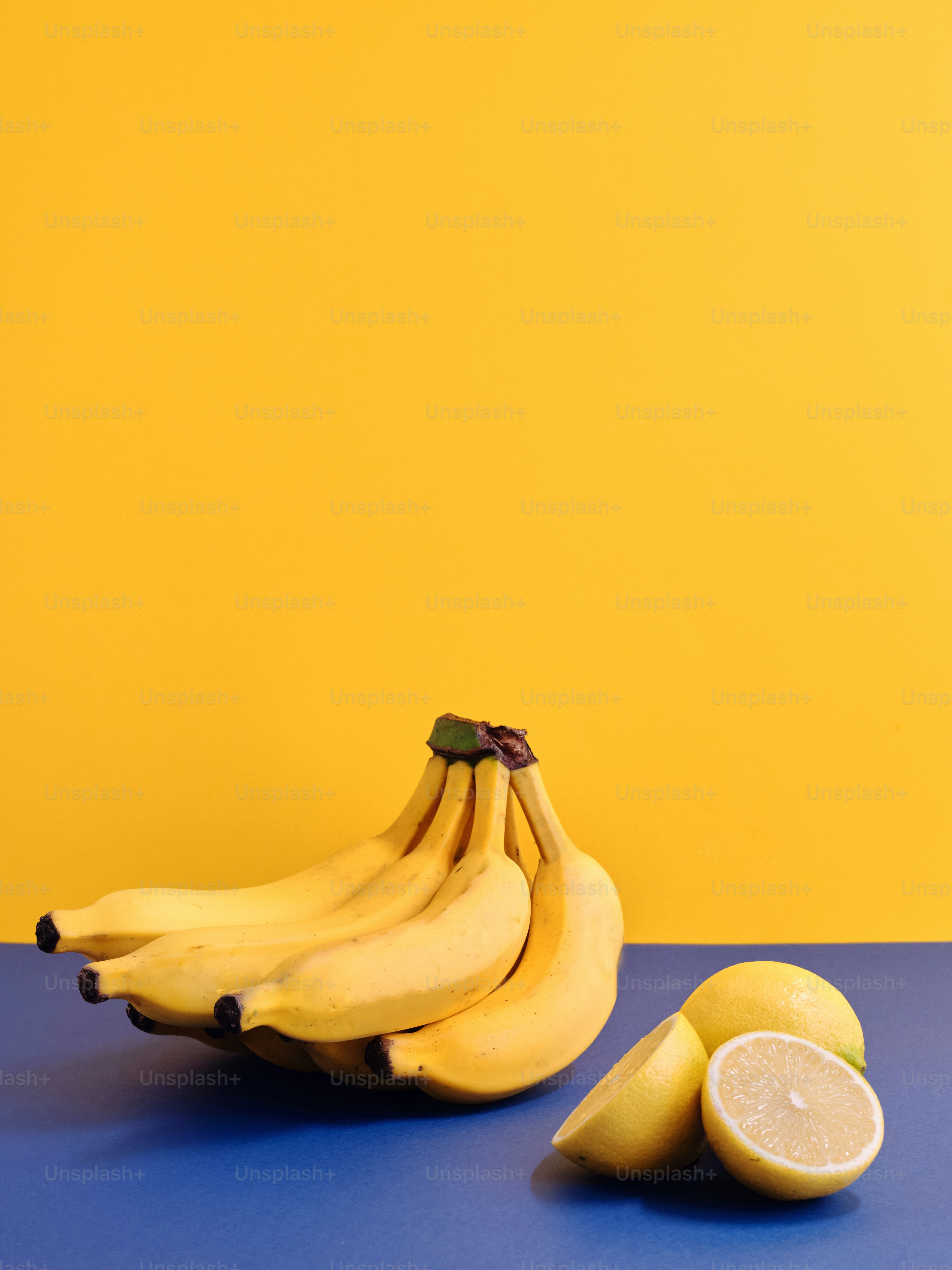 a bunch of bananas and two lemons on a table
