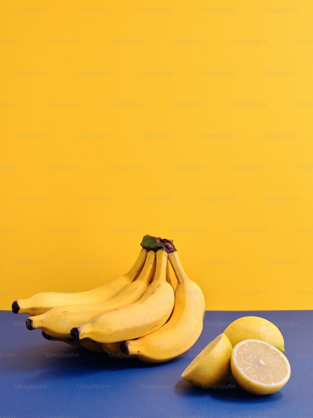 um cacho de bananas e dois limões sobre uma mesa