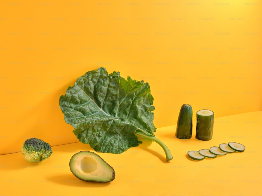 a green leafy vegetable next to a sliced avocado