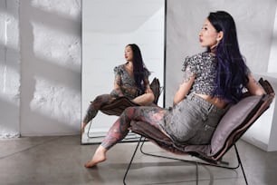 una donna seduta sopra una sedia accanto a uno specchio