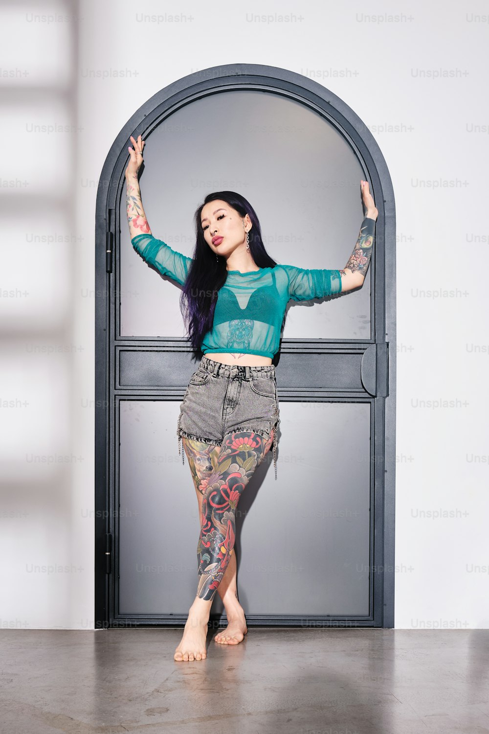 a woman with tattoos standing in front of a door